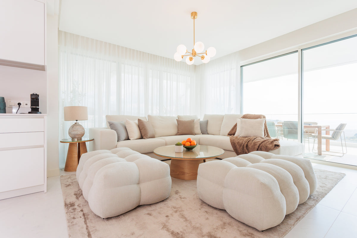luxury comfortable interior design for living room with cream sofa, soft ottomans, elegant rug, pillows, coffee tables available in bali villas real estate, cala de mijas interior design.