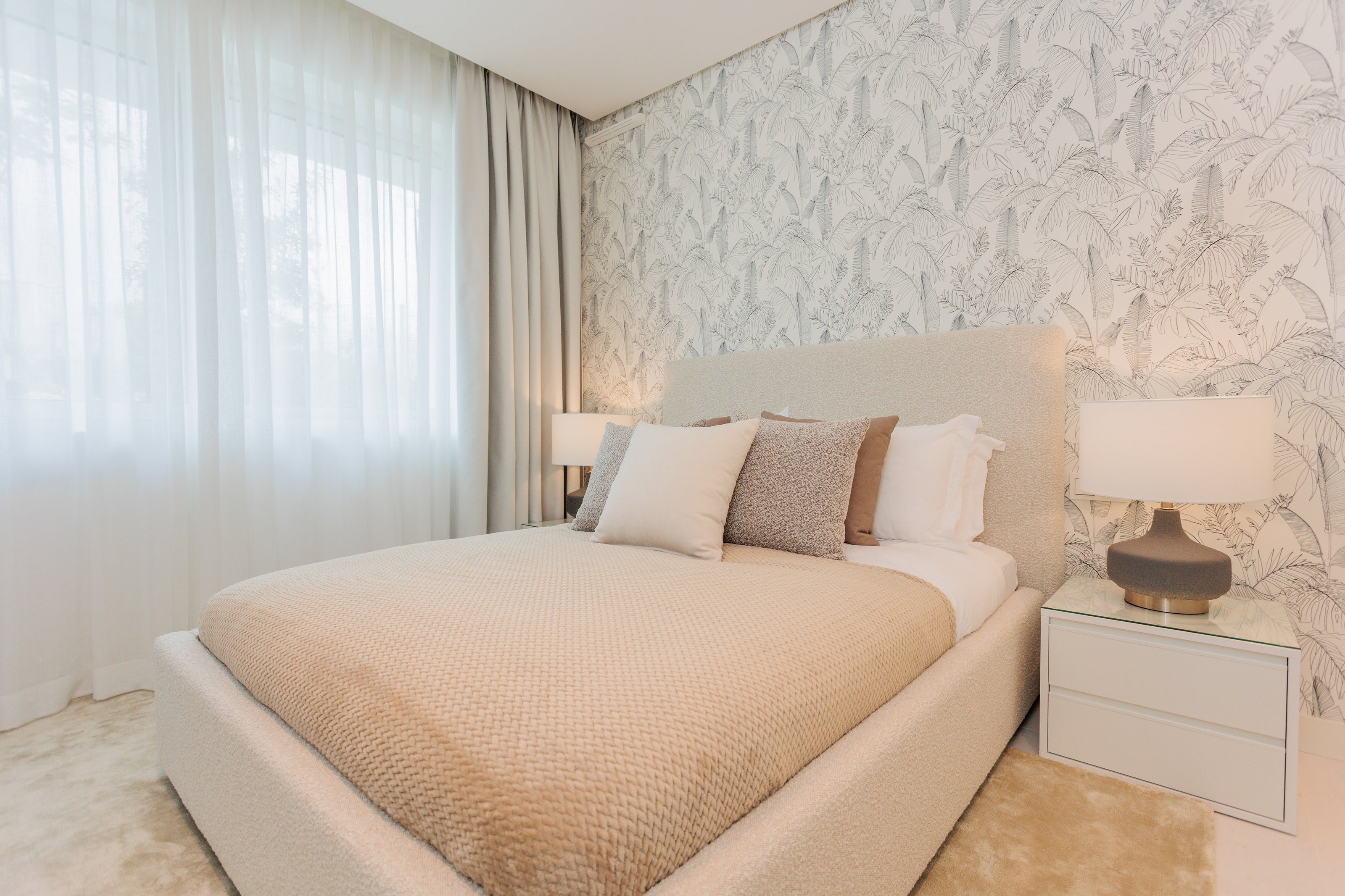 luxury interior design, home design with cream colored bed, pillows, clean wallpaper, bedside table, modern table lamps, made to measure curtain available in benahavis, marbella, malaga, costa del sol, bel air.