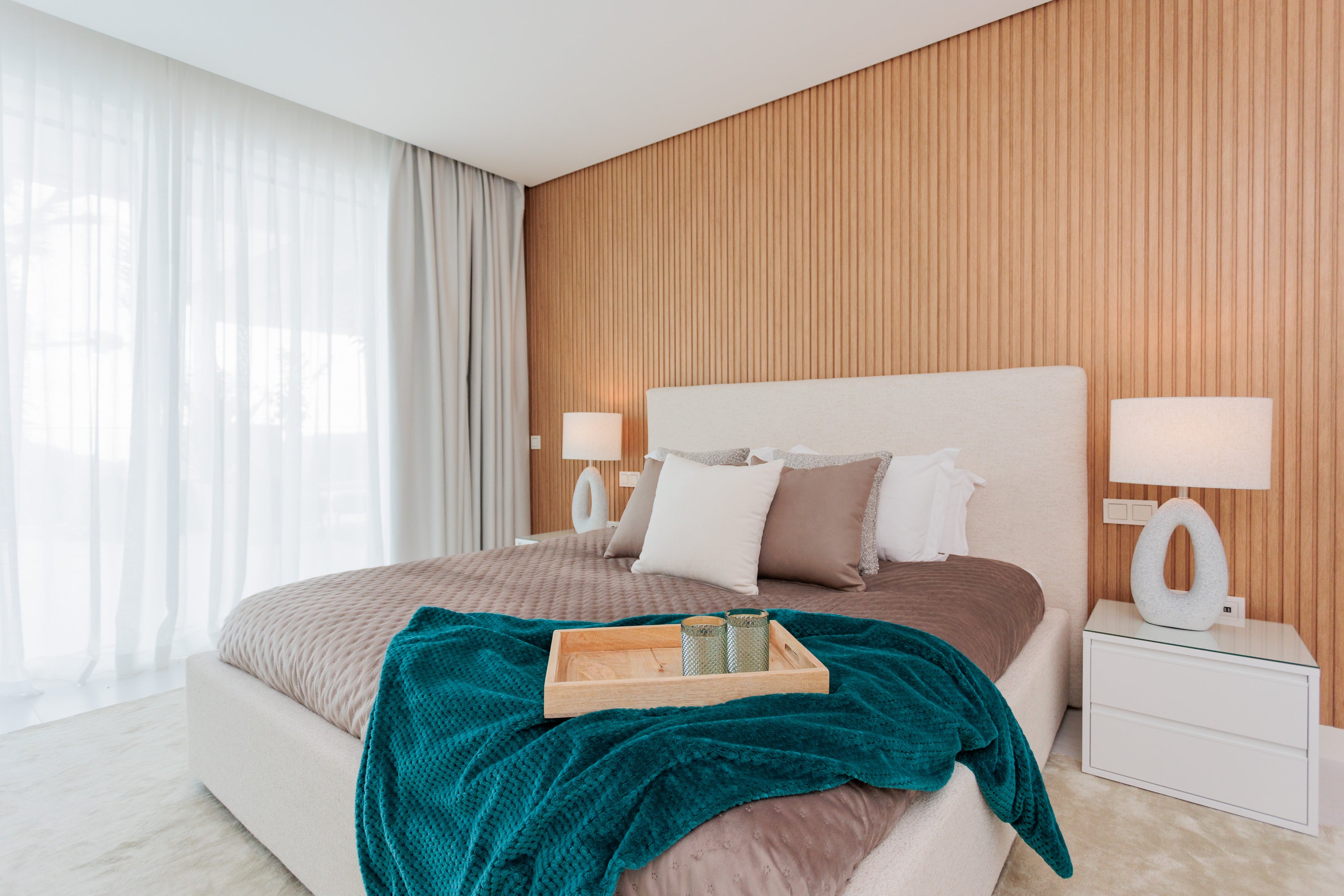 luxury interior design for bedroom with wooden panels, beige cream bed, headboard, brown bed with green accent tones and minimalist bedside table available in el higueron, benalmadena, marbella, malaga, costa del sol.