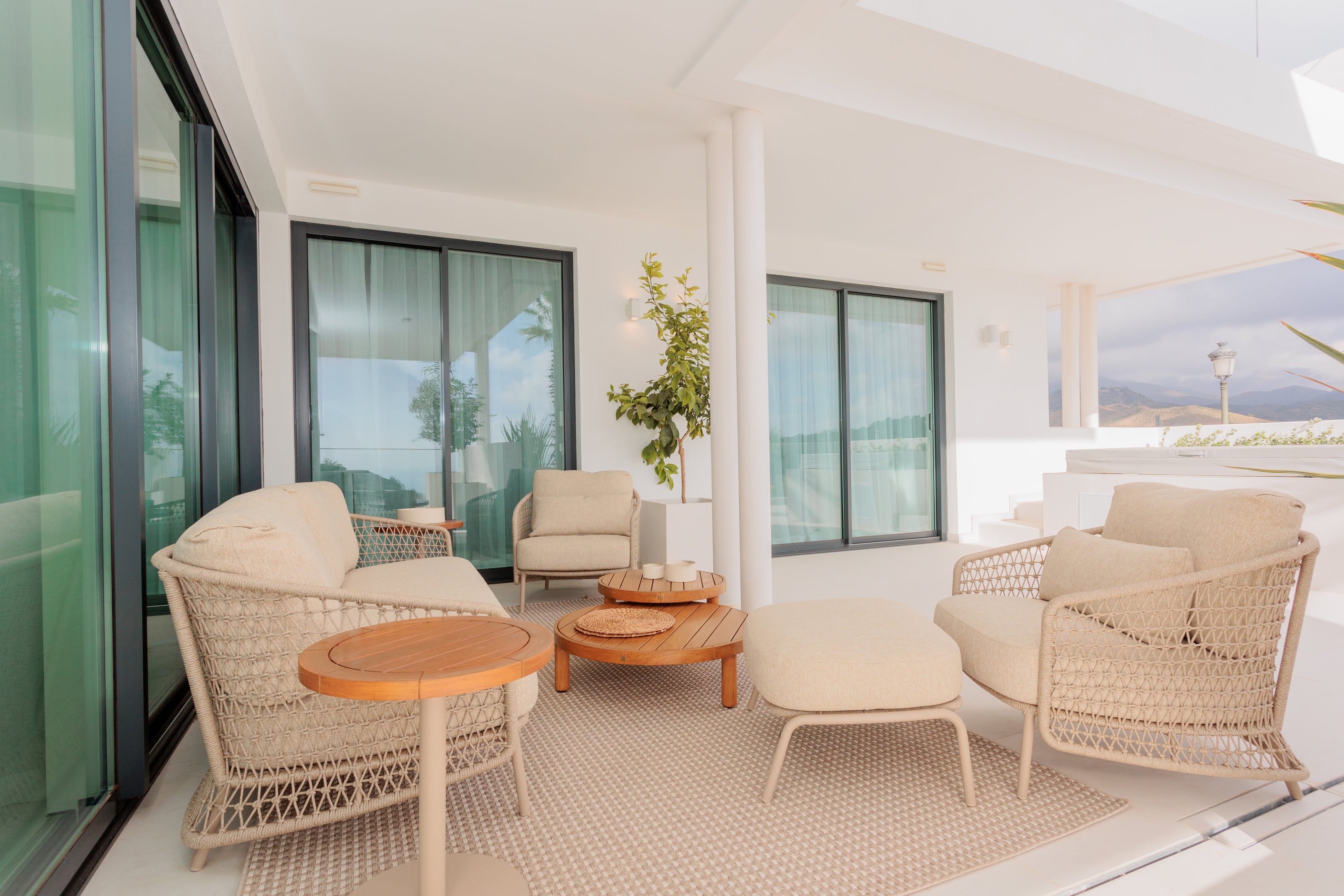 outdoor interior design with luxury outdoor furniture, living set with 2 seater sofa, armchairs, wooden coffee table and side table with rug available in benahavis, marbella, malaga, costa del sol.