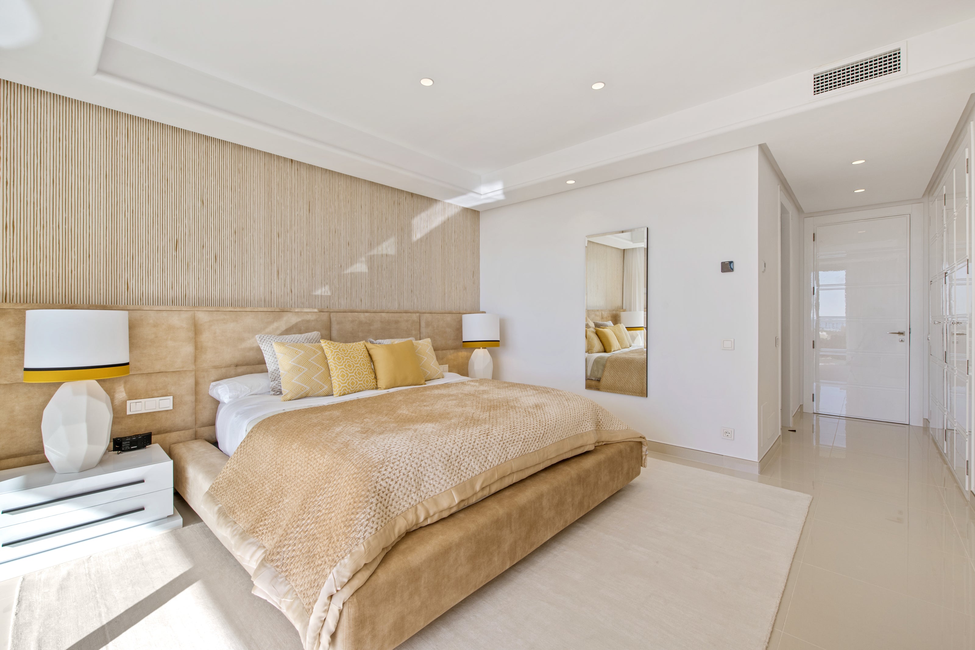 Custom made yellow bed with stylish headboard, bedside tables, table lamps yellow, and classic beige rug. Interior design modern available in cancelada, Malaga, marbella, estepona, calahonda.