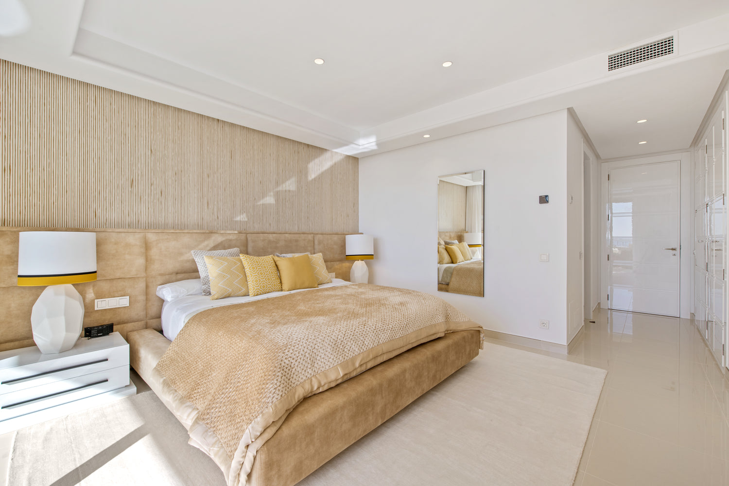 Custom made yellow bed with stylish headboard, bedside tables, table lamps yellow, and classic beige rug. Interior design modern available in benahavis, Malaga, marbella, estepona, calahonda.