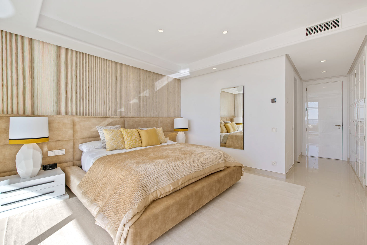 beautiful yellow modern bedroom interior design with long headboard and beige rug, bedside table with elegant table lamps available in el higueron, malaga, marbella, costa del sol, benahavis.