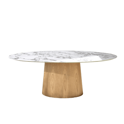A round coffee table with a white marble-patterned top and a tapered light oak wood pedestal base, set in a bright minimalist room with white walls and a light carpet.