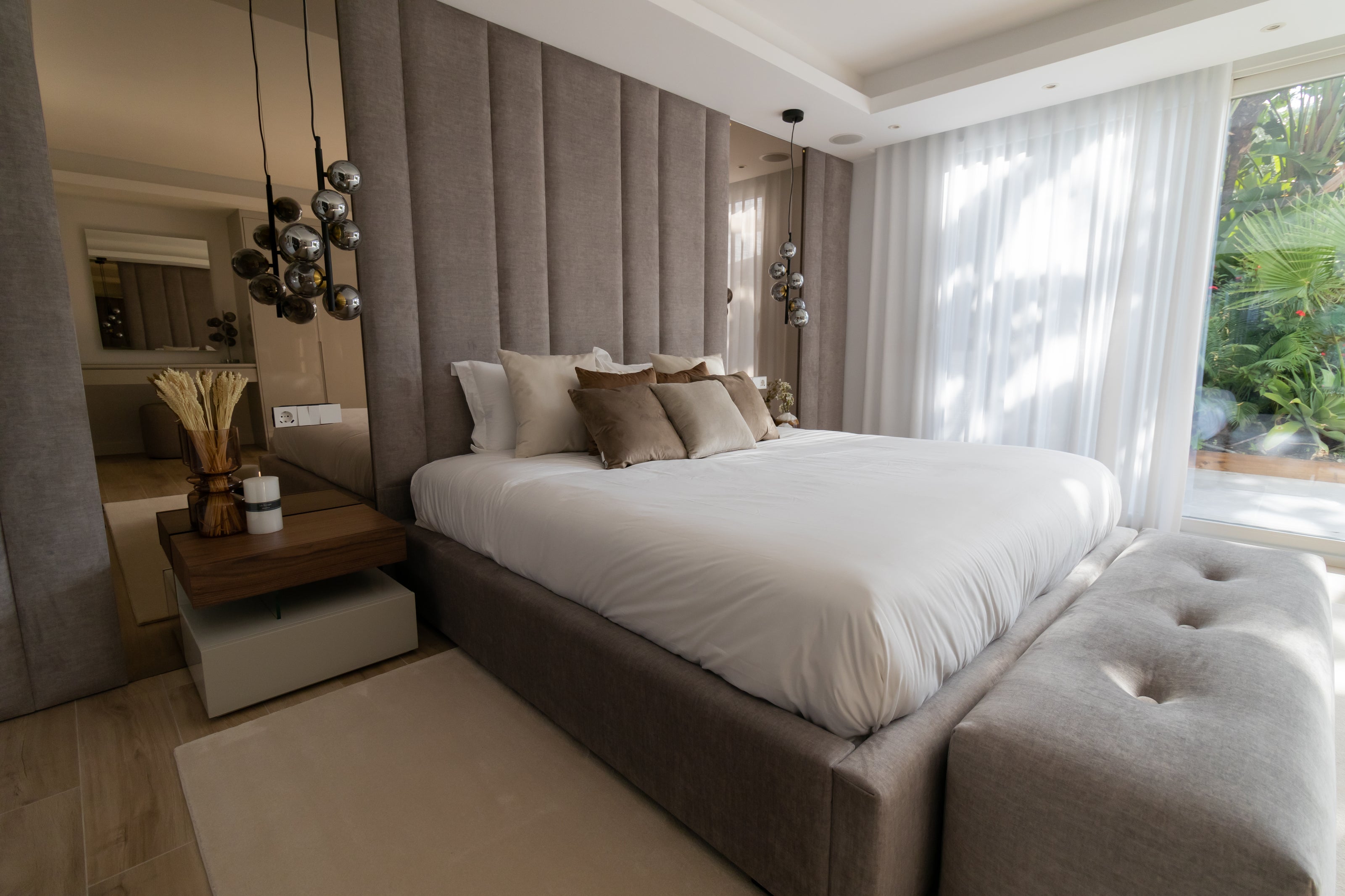 Elegant contemporary interior design, home design for bedroom with bronze mirror, tall headboard, bed, bedside table, ottoman, rug and ceiling lamp available in el higueron, marbella, malaga, costa del sol.