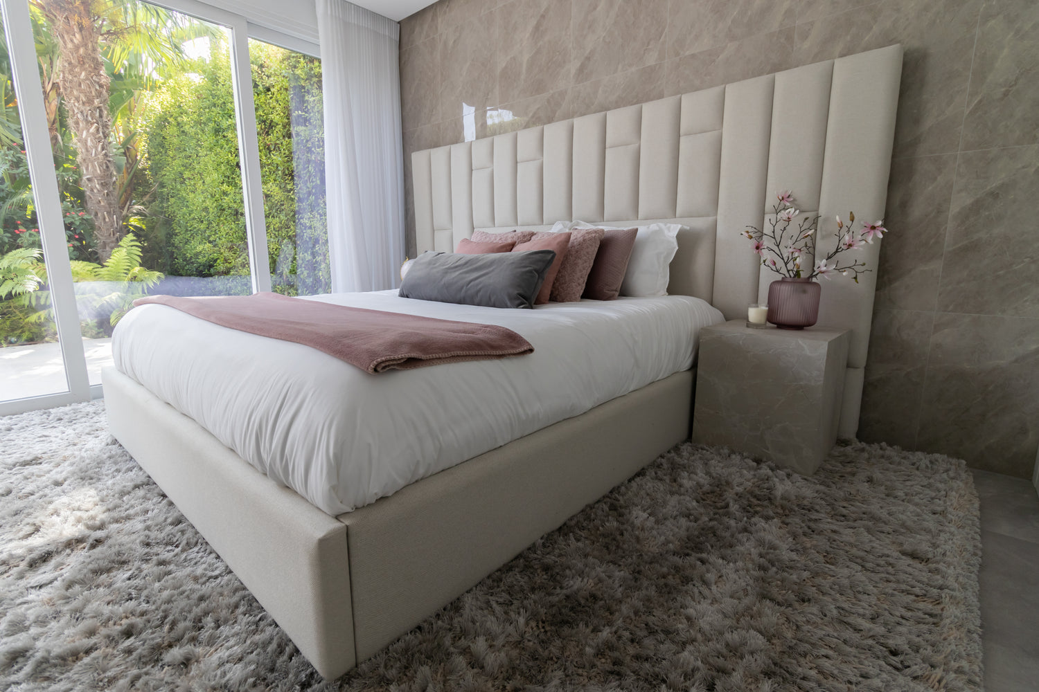 bedroom interior design with headboard, bed, fluffy rug with fur and pink and grey pillows with marble side table available in brisas del mar estepona, marbella, malaga, costa del sol.